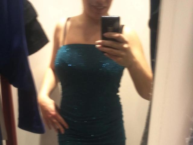Hotblondebabe-sex in a tight, sparkly teal dress, showing off her tits and ass in a mirror selfie. She's holding a phone, smiling, with one hand on her hip.