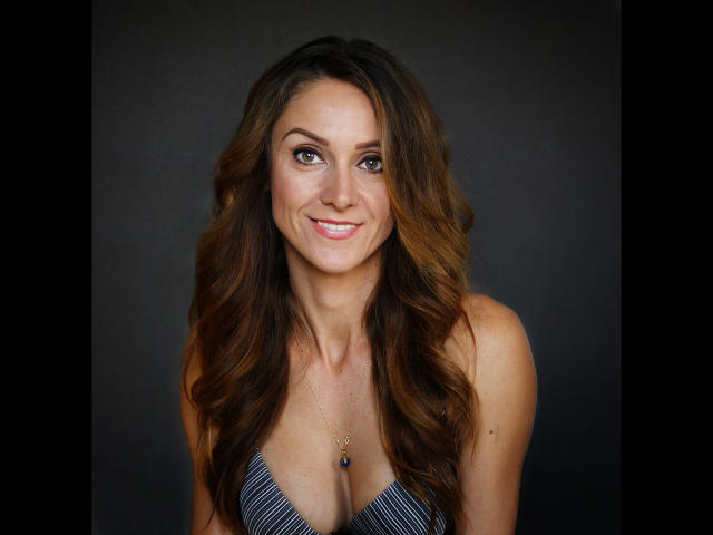 LarisaRais-hot with long wavy brown hair, smiling, wearing a striped top, showing her tits, green eyes, and a necklace with a small blue gem.