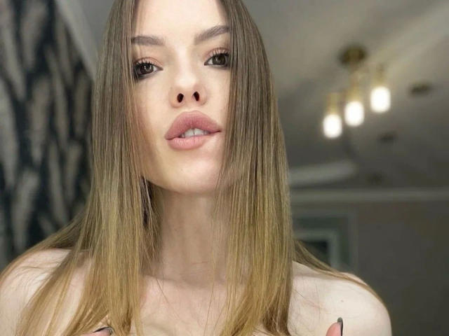 Eva24-hot with long brown hair, wearing a black strapless crop top, showing her boobs, and a black skirt, taking a mirror selfie with a pink phone.
