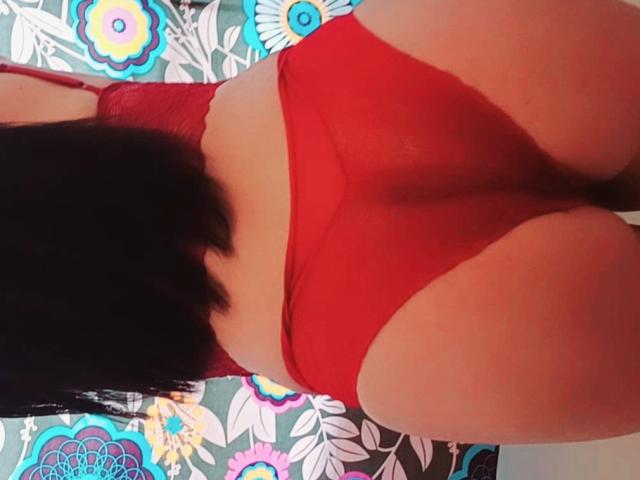 KarliWow's ass in red mesh underwear, showing her buttcheeks and a hint of her pussy, with black hair falling over her back. Image focuses on her lower body.