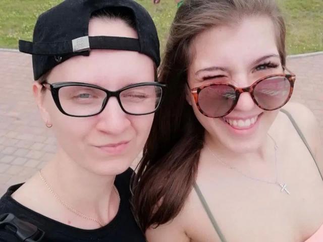 DoubleloveXXX-hot with glasses and a black cap, and DoubleloveXXX-hot with tortoiseshell sunglasses and a cross necklace, both smiling.