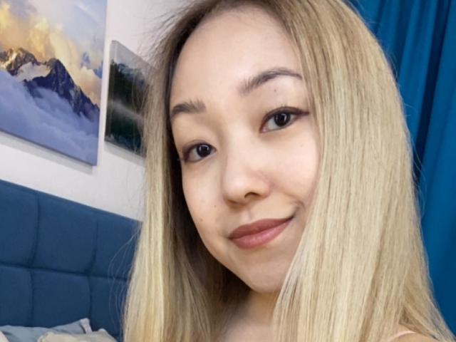 RenyLime a les cheveux blonds, les yeux marrons, et elle sourit avec du rouge à lèvres rose. Elle a un joli visage et regarde l'appareil photo. Ses seins ne sont pas visibles..