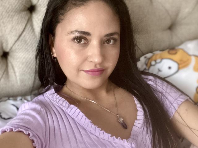 Hopeless with long black hair, pink lipstick, and a purple ribbed shirt, wearing a silver necklace with a purple stone, has a cute face and small tits.