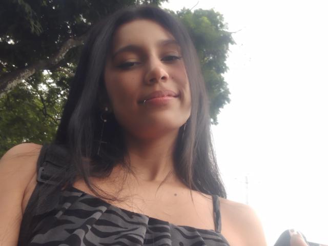KataleyaMansson has long black hair, a nose piercing, and a subtle smile. She's wearing a zebra-patterned top with thin straps, looking slightly down. Her ass is not visible.