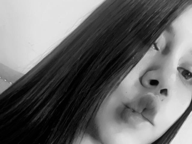 Selfie en blanco y negro de Stephanie Davies con cabello largo y oscuro, labios carnosos y ojos ligeramente entreabiertos, mostrando una nariz sutil y rasgos faciales suaves. Su nariz está ligeramente levantada..