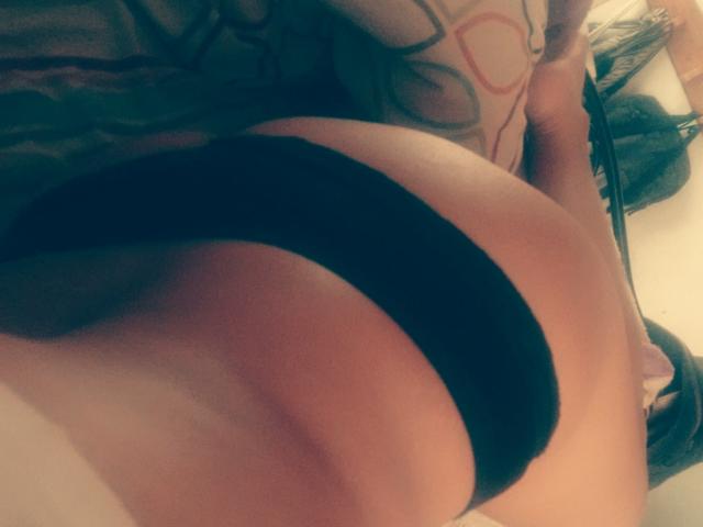 SexyLatinMadura's butt in black panties, tattoo on side, upper body out of frame, slightly blurred, warm lighting, soft texture, skin tone medium, subtle shadow.