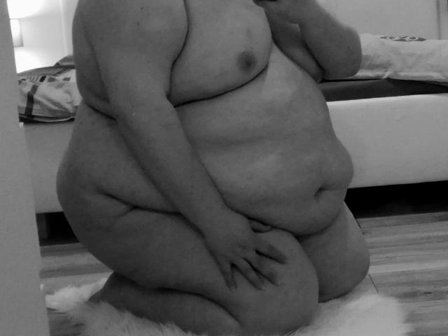 Meike4you-hot kneeling nude with large, saggy tits, fat belly, and curvy ass, holding her hand on her thigh, in a black-and-white selfie.