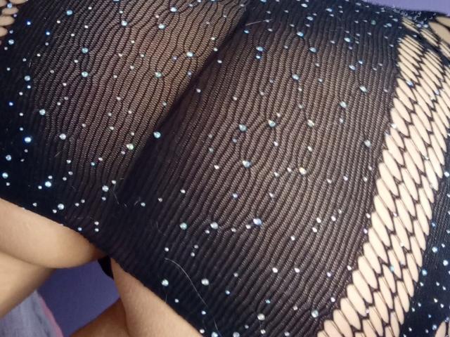 MadissonS' ass in a black fishnet dress with white and blue sparkling dots, showing her bare butt through the net. The fishnet is tight with a zipper side.