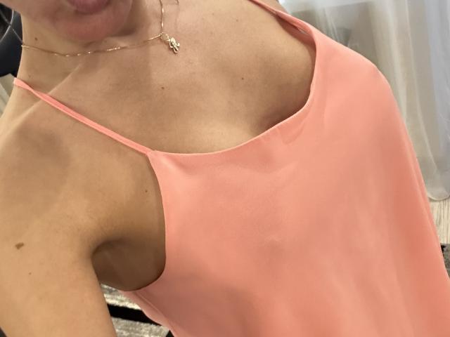 BellaJulls wearing a pink camisole, showing her tits with thin spaghetti straps, a gold necklace, and a small mole on her right shoulder. Her skin is light.