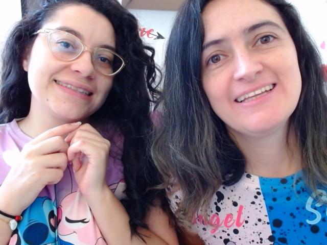 LunaVenus with curly black hair, glasses, and pink shirt stands next to LunaVenus with straight brown hair, smiling, wearing a blue speckled shirt. Both have cute, happy faces.