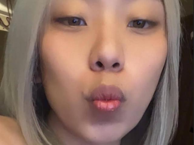 MissSultryAya has pale skin, grayish-white hair, and is pouting her pink lips with a slightly open mouth in a selfie. Her brown eyes are looking forward.