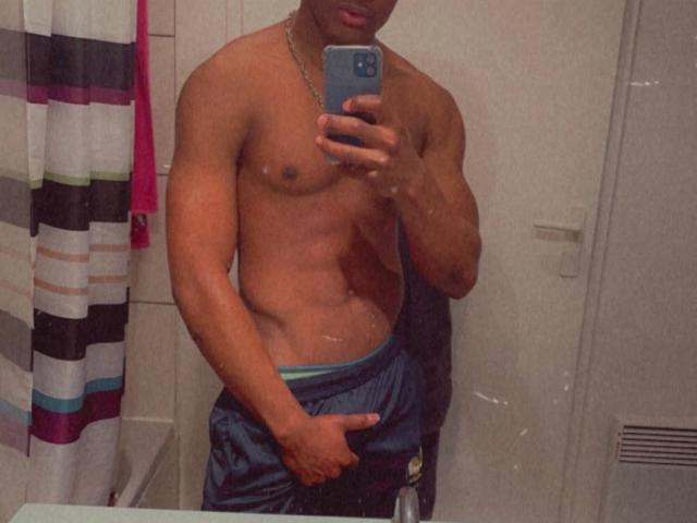 SoulXSky, senza camicia, muscoloso, con la pelle scura, che tiene il telefono per un selfie allo specchio, pantaloni blu, mano che copre l'inguine, collana a catena, tenda da doccia a righe a sinistra, bagno, superficie riflettente..