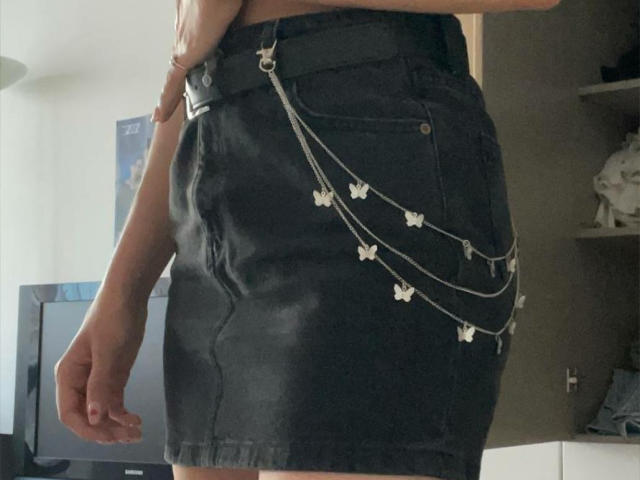 La gonna di jeans neri di Keiri, con catene a forma di farfalla metalliche appese alla cintura. Visibile dalla vita all'altezza della coscia. La gonna è leggermente usurata, mostrando la sua texture. Il braccio di Keiri è rilassato..