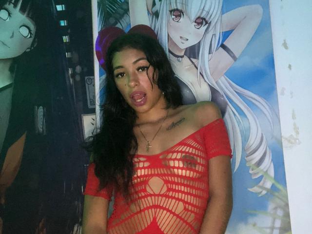 KratosXLadies with long black hair, wearing a red, see-through mesh top, exposing her tits and nipples. She has a tattoo on her left chest and a cross necklace.