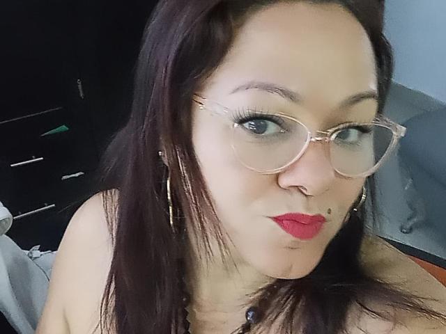 LunaSky69 a les cheveux brun foncé, une peau claire, porte des lunettes roses, du rouge à lèvres rouge et un anneau de nez. Elle fait la moue et a une petite tache de beauté sur la lèvre supérieure..