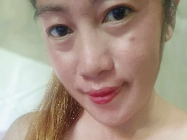 Xenia69 has a cute face with light skin, brown eyes, and a small zit on her cheek. Her lips are slightly pink, and she's smiling softly.