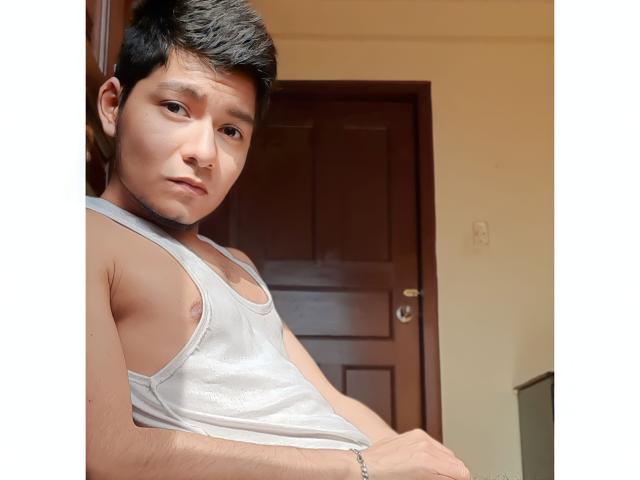 Lexden, un ragazzo asiatico carino con i capelli neri corti, indossa una canotta bianca, che mostra i suoi piccoli capezzoli, e un leggero, sexy e sicuro sorriso..