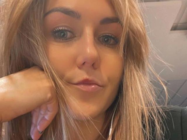 GanzNettePaola-hot has blonde hair, blue eyes, and is resting her chin on her hand with a slight smile. Her eyebrows are thick and her lips are glossy.