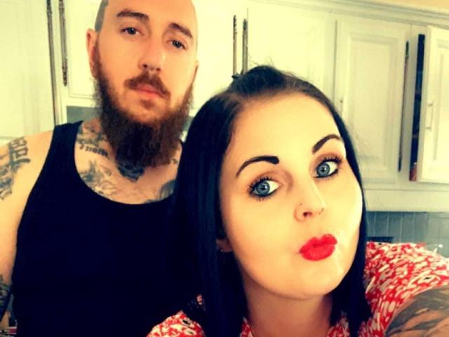 GoranMonica, con gli occhi azzurri, il rossetto rosso e i capelli neri, che fa la smorfia. GoranMonica calva, con la barba, in un canottino nero, con tatuaggi sul petto e sulle braccia, che sta dietro di lei..