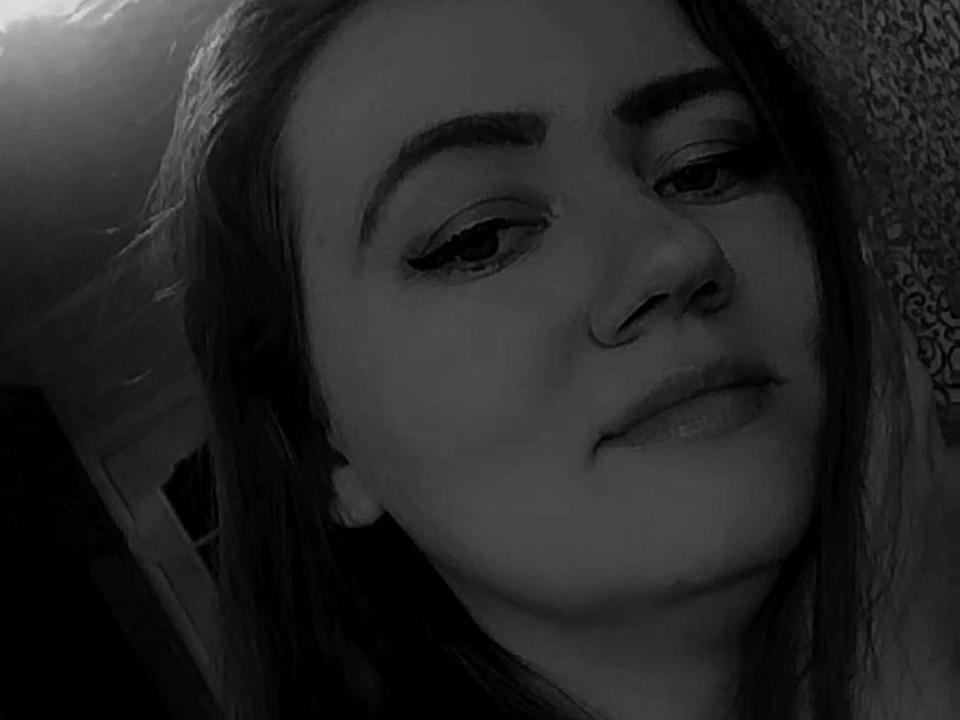 Black-and-white selfie of KristalSexyShy with half-closed eyes, subtle smile, and long dark hair, showing eyeliner and a small nose ring. Her eyebrows are thick and slightly raised.