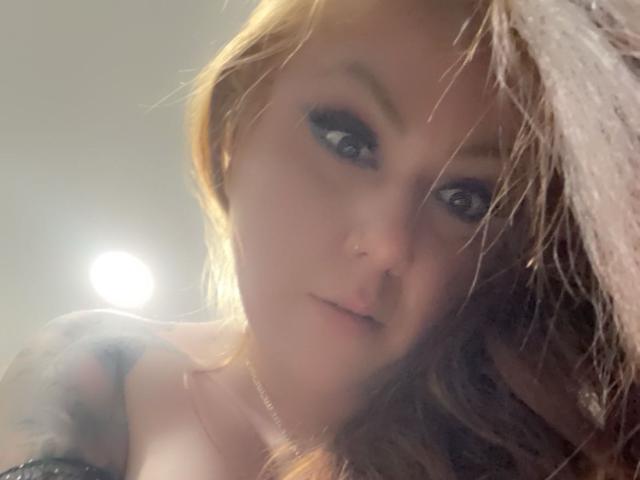 Blush69 tiene el cabello castaño claro, ojos azules y un piercing en la nariz. Lleva delineador de ojos negro y una blusa negra, con un tatuaje discreto en el hombro izquierdo..