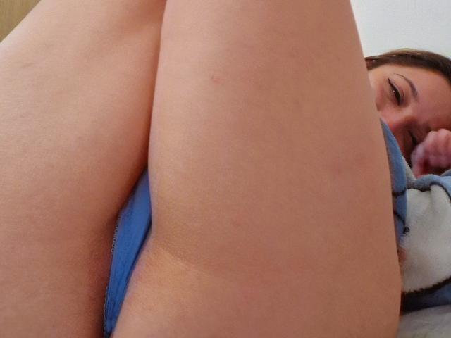 ErinFoxy's butt is in the foreground, wearing blue panties, with her face partially visible on the right, looking up. Her thighs are spread, showing her pale skin.