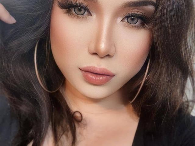 SuperHotVenna's face is super hot, with glossy pink lips, grey eyes, long dark wavy hair, and large hoop earrings. Her skin is smooth and her makeup is on point.