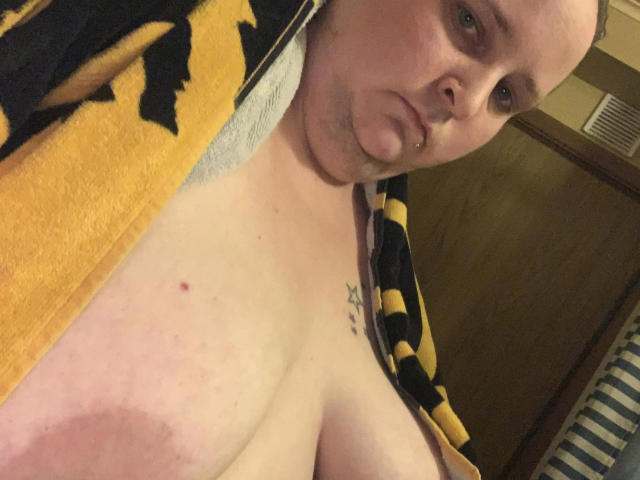Kiramaus88-hot with a bald head, piercled lower lip, and a tattoo on their chest, showing their large bare boobs, wearing a yellow and black striped robe.