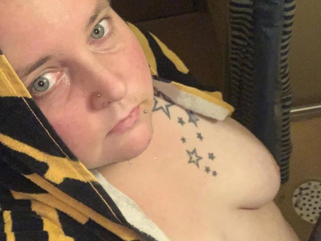 Kiramaus88-hot with a towel over her head, showing her tits and a star tattoo on her chest, has a nose ring and a lip piercing, looking at the camera.