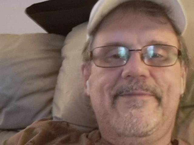 A middle-aged dude with glasses, a mustache, and a beard wearing a beige cap, smiling at the camera. His ass is not visible.