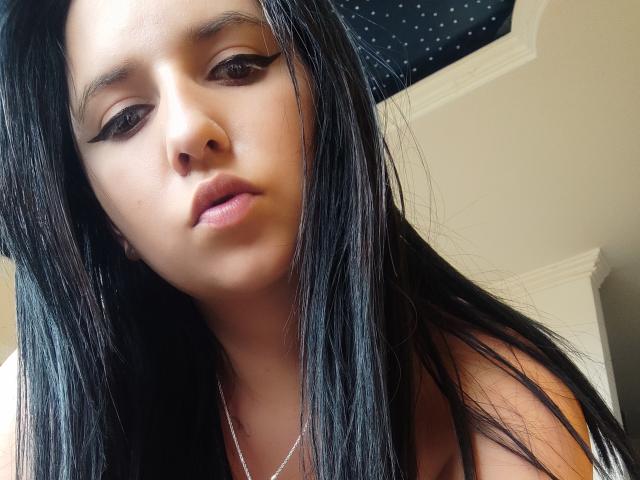 Kkatalina has long black hair, winged eyeliner, and a serious expression. She's wearing a silver necklace and has a slightly parted, sexy, pouty mouth.
