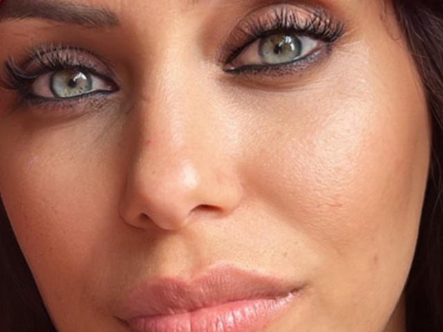 ChouLove's face, showing her green eyes, long eyelashes, pink lips, and slightly textured skin with a subtle smile. Her brown hair is partially visible.