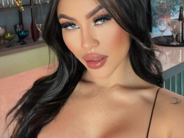 JunneLiu has long black hair, blue eyes, and full pink lips. She's wearing a nose ring, has thick eyelashes, and a crescent moon tattoo on her right shoulder.