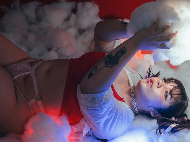 LallyyPop con tatuaggi, sdraiata su una soffice nuvola bianca, indossa una maglietta rossa, biancheria intima in pizzo bianco e un collare, tiene la nuvola, luci rosse e blu sulla pelle, guarda in alto, sexy, formosa..