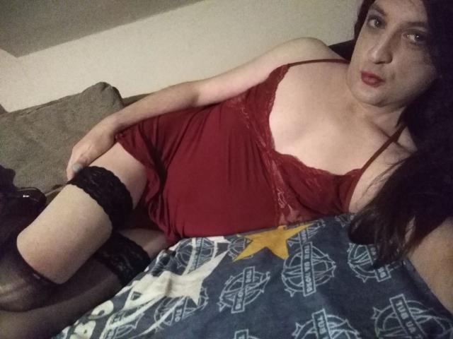 ZackaSissy20 – heiß in roter Dessous, schwarzen Netzstrümpfen und mit einem verführerischen Blick, liegt auf einem Sofa mit einer blauen Decke mit weißen und gelben Sternen..