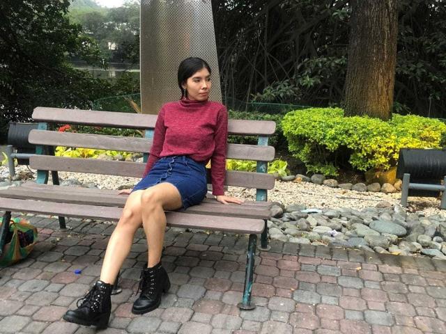 MileyWatson sits on a wooden bench, wearing a red turtleneck, blue denim skirt, and black boots, with her legs crossed, looking to the side. Her ass is visible.