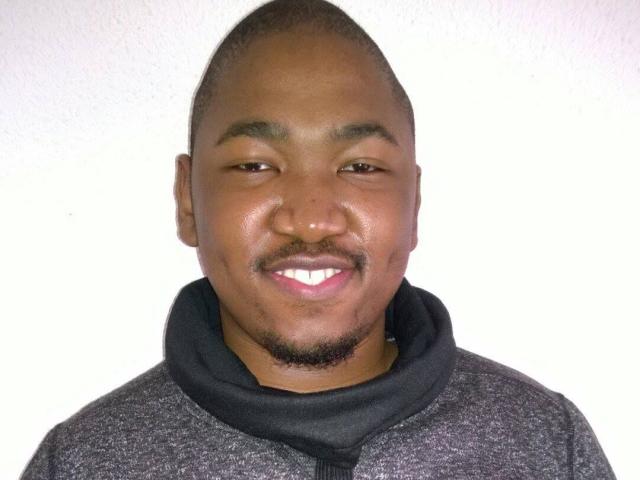 BigDickCya261, a chubby black dude with a shaved head, small goatee, and black shirt, smiling with white teeth. His nose is slightly upturned.