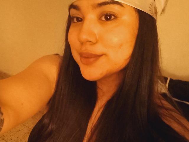 SteffanyTaylor has long black hair, a white headband, and is smiling with a slight pimple on her right cheek. Her brown eyes and medium skin are visible.
