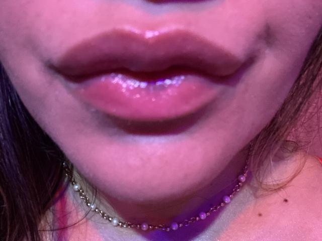 LiaHot69's glossy pink lips are centered in the frame, with a small gold chain necklace and pink beads, her slightly parted mouth showing a hint of her upper teeth.