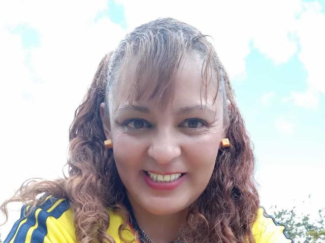 AmandaHotL has curly brown hair, yellow and black striped shirt, orange earbuds, smiling with pink lipstick, and wet hair from the rain. Her tits are small and cute.