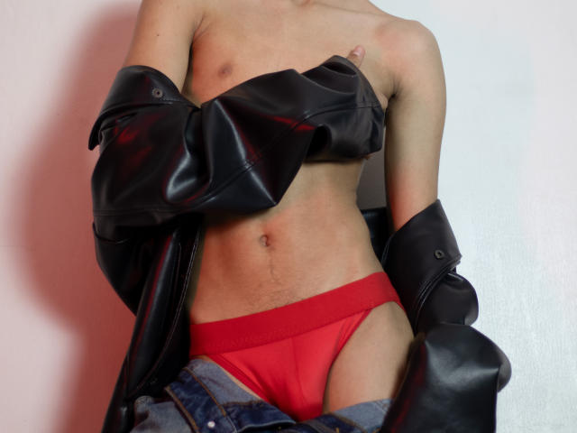 DenisBachh with bare tits, red panties, black leather jacket falling off shoulders, blue jeans around thighs, light skin, flat stomach, nipple visible, no face shown.
