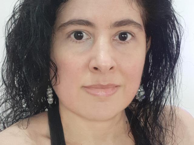 PamyToLike has wet black hair, brown eyes, light skin, small nose, and pink lips, wearing black halter and silver earrings, looking straight at the camera.