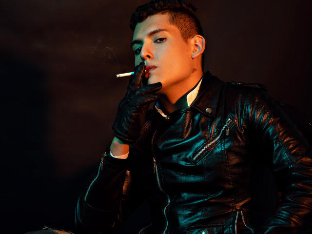 DomStravelers with a cigarette in their mouth, black leather jacket, and gloves, holding their chin, short dark hair, intense gaze, dark background, leather texture, smoky atmosphere.