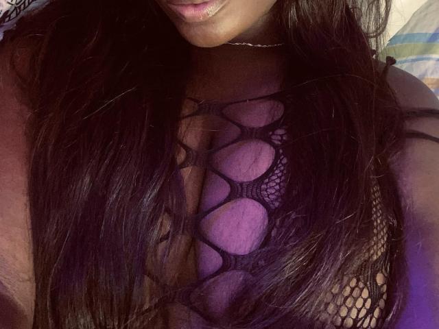 MeganSaenz's dark, wavy hair covers her tits, which are visible through a black, fishnet-style, crotchless top. Her skin is tan, and she's wearing a thin choker.