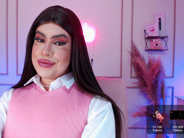 ImNicol heeft lang donker haar, roze lippenstift en draagt een roze trui over een wit shirt. Haar make-up is opvallend, met dikke wenkbrauwen en lange wimpers. Borsten zijn niet zichtbaar..