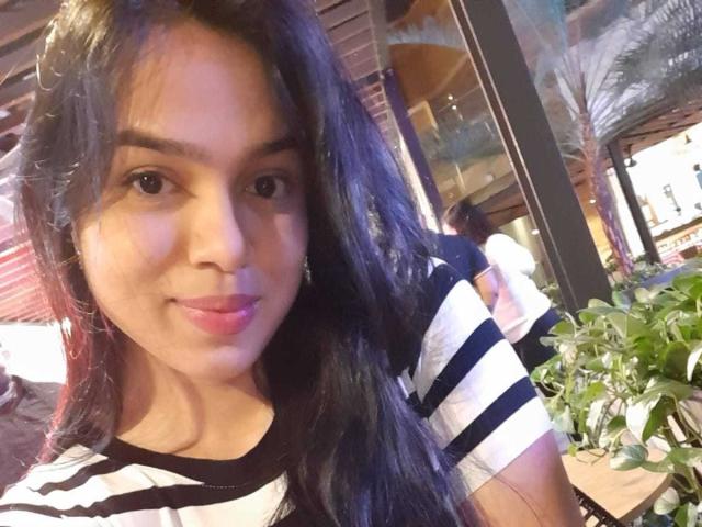 AnyaCathy has long black hair, brown eyes, and a slight smile. She's wearing a black and white striped shirt, showing her tits and cute ass. She's indoors.