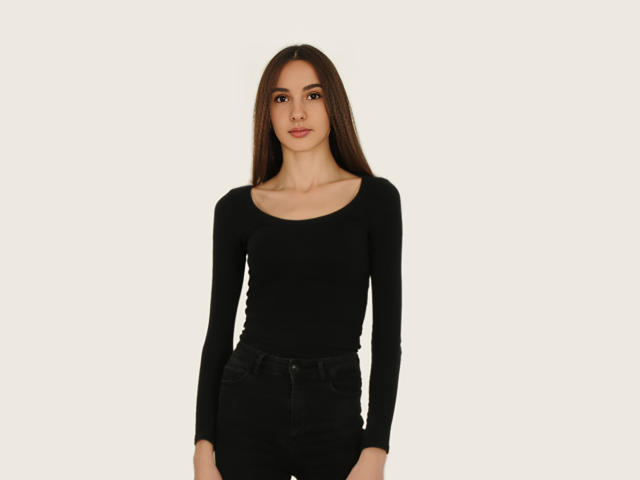 VioletaAndLeo has long brown hair, wearing a tight black long-sleeve shirt and black jeans, standing against a plain white background. Boobs, ass, pussy not visible.