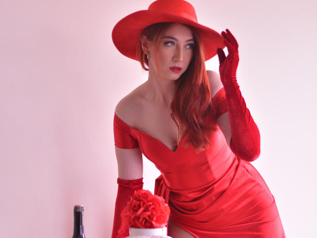 LauraDante in a red dress, hat, and gloves, holding roses, with her tits slightly showing, looking to the side, touching her hat, and wearing red lipstick.