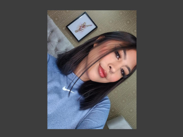 CarlaRusso has black hair, light brown skin, and wears a blue Nike shirt. She's smiling with red lipstick, looking at the camera. Her tits are small and cute.