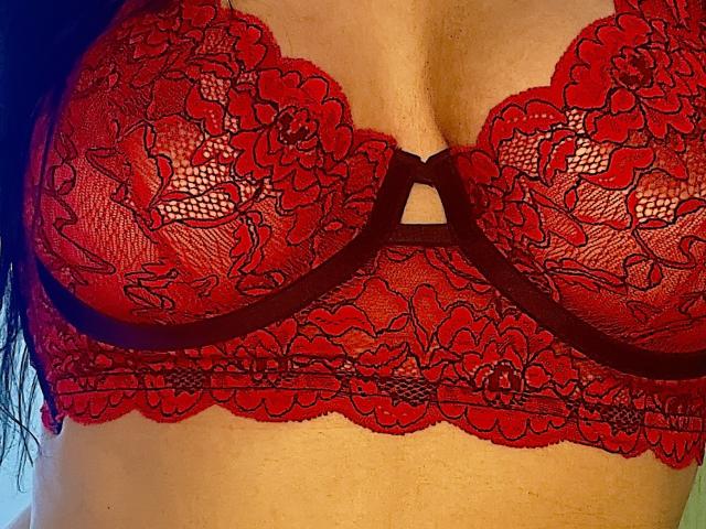Azule's red lace bra with floral patterns covers her tits, featuring black trim and a keyhole cutout. Her skin is slightly wet. Red, lace, tits, bra.